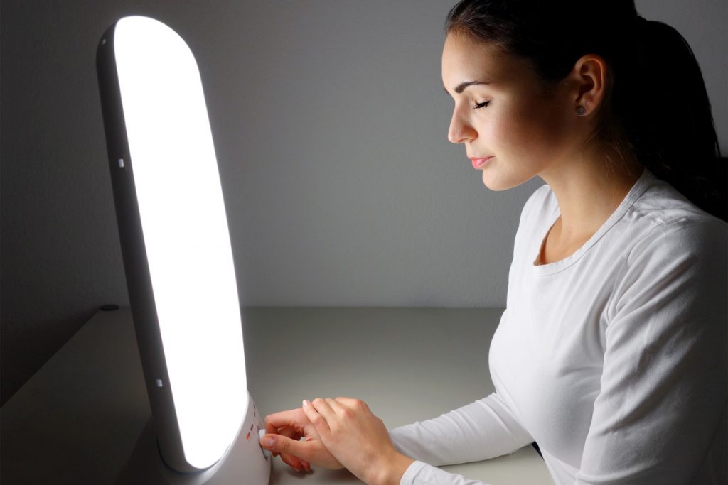 Young woman administering a light therapy agains winter depression